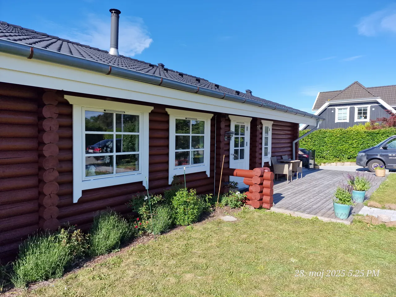 Rødt bjælkehus med terrasse og skorsten