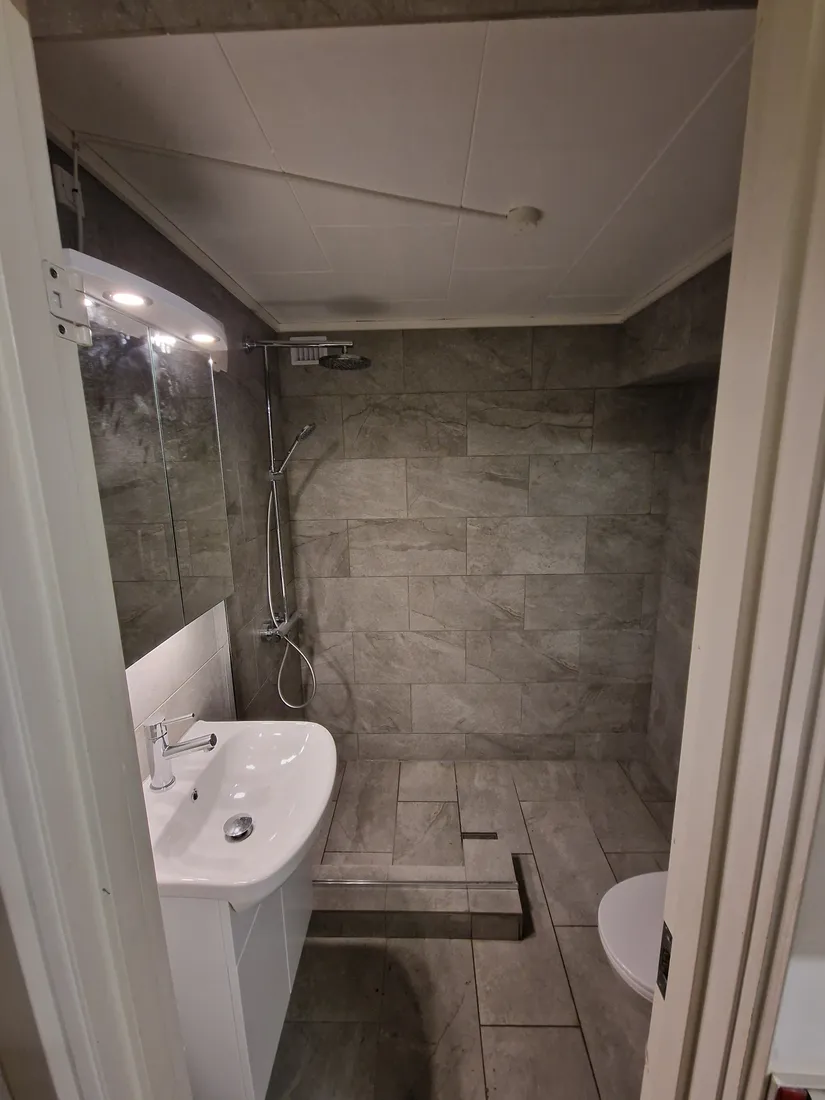 Nyt gråt badeværelse med indbygget bruser og håndvask, efter renovering