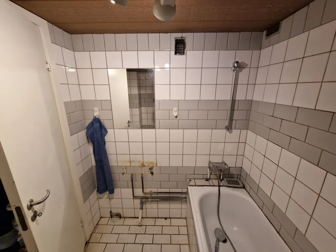 Gammelt hvidt badeværelse med badekar, før renovering