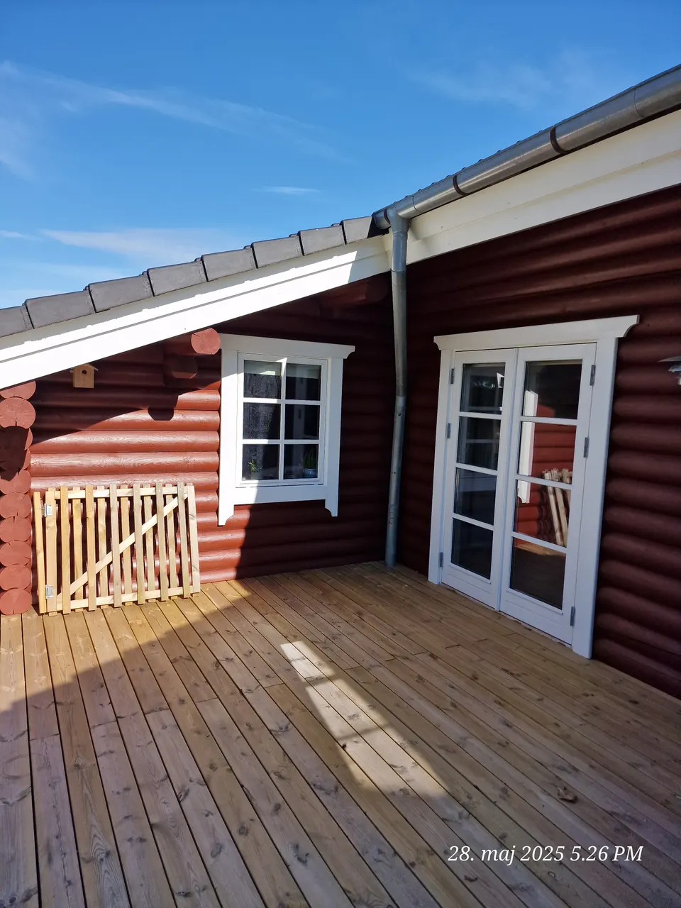 Træterrasse ved rødt bjælkehus